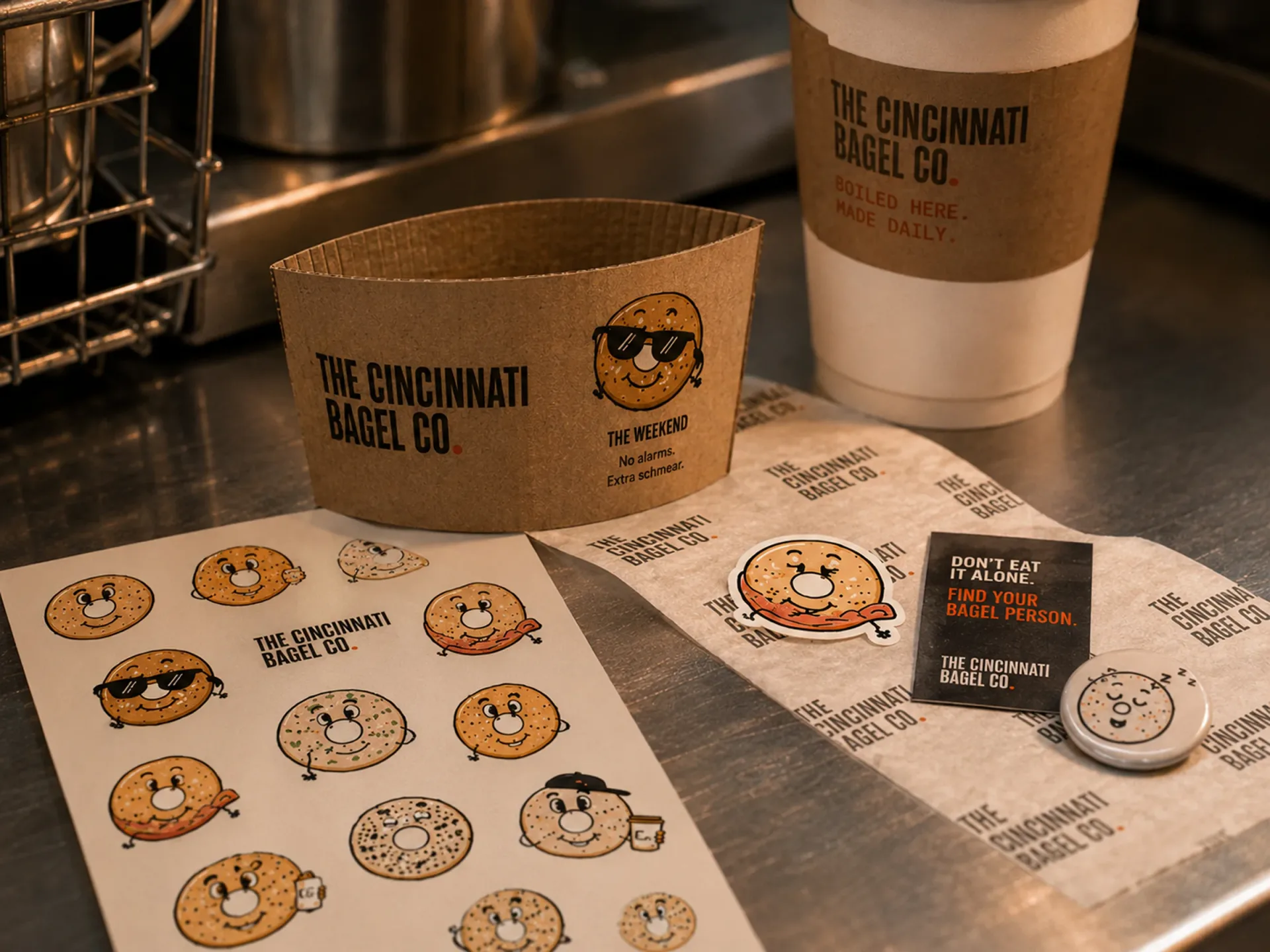 The Cincinnati Bagel Co. — Cincinnati Bagel Co. character stickers, coffee cup, receipt, and paper goods on a counter
