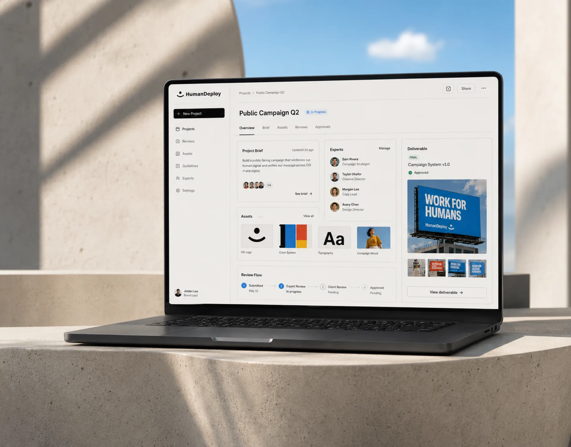 HumanDeploy — The HumanDeploy product on a laptop — a 'Public Campaign Q2' view with brief, assigned experts, an approved deliverable, and a staged review flow