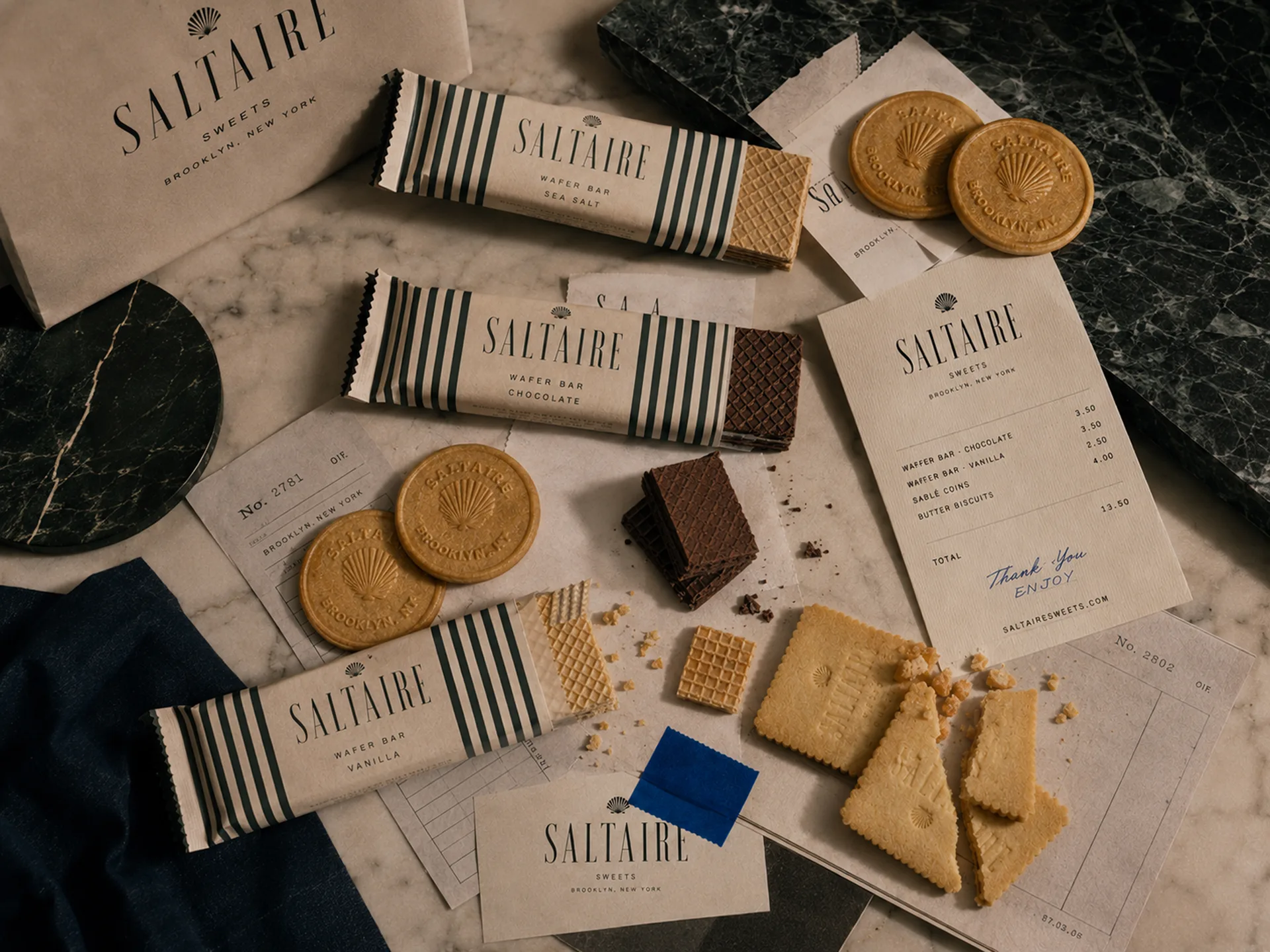 SALTAIRE — SALTAIRE wafers, chocolate bars, stamped cookies, receipts, and handwritten notes spread across marble