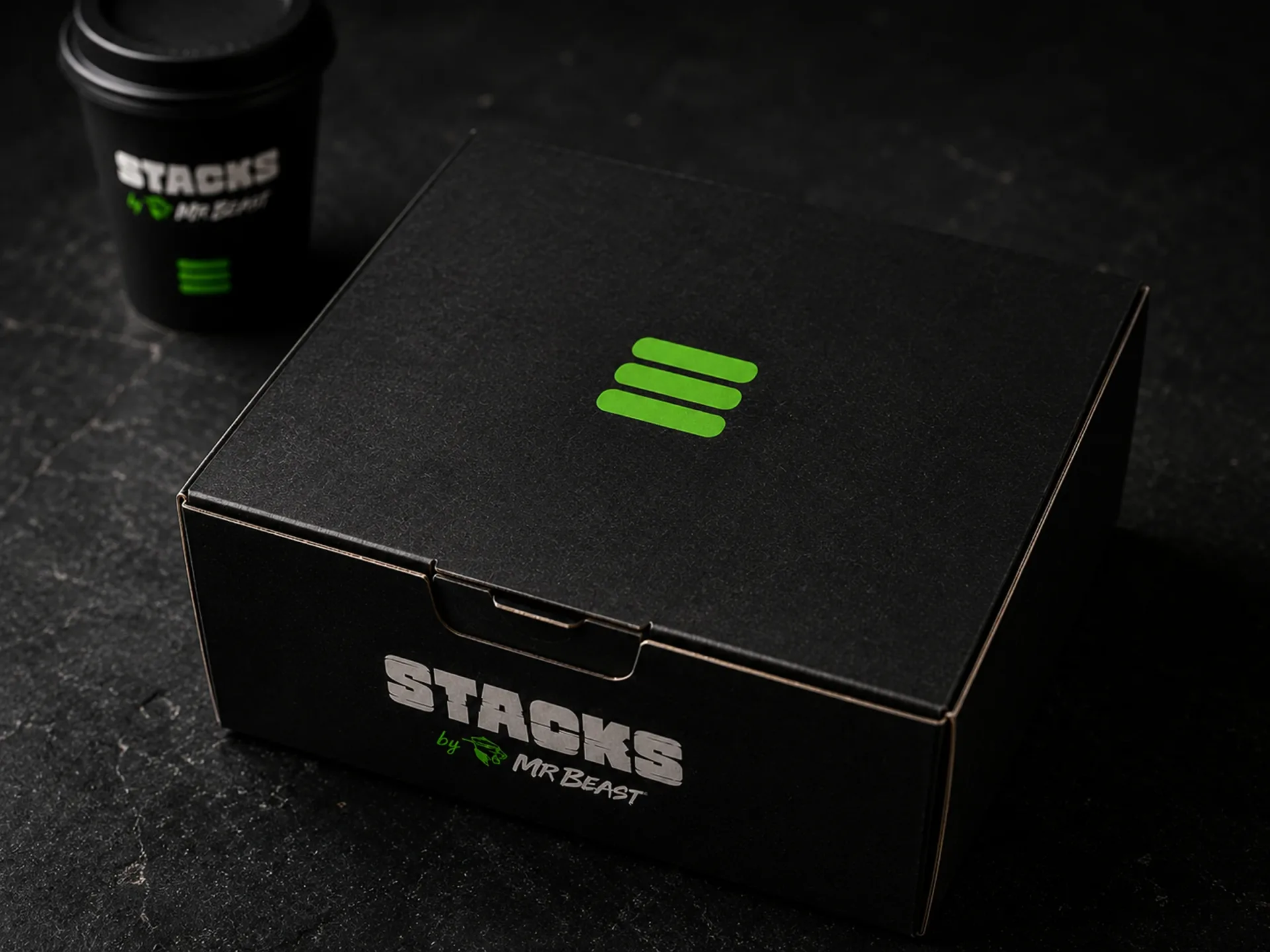 Stacks — Stacks black takeout box and coffee cup on a dark counter with green stack mark