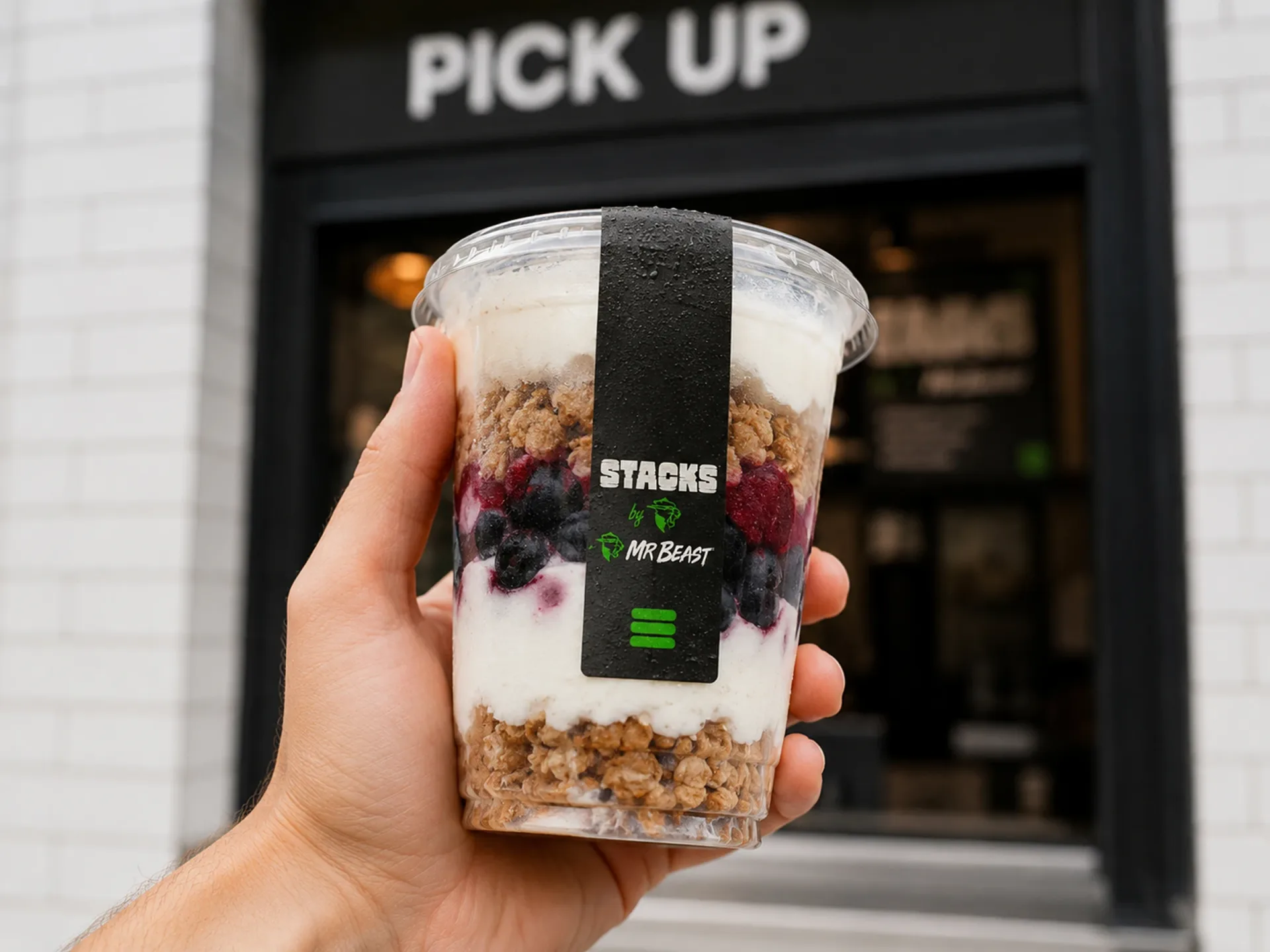 Stacks — Hand holding a Stacks by MrBeast parfait cup in front of a pickup window