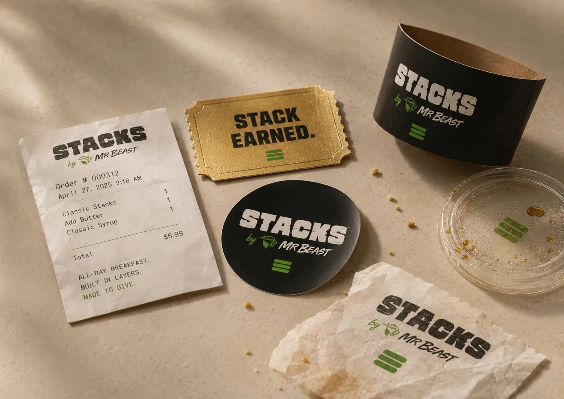 Stacks — Stacks receipt, Stack Earned ticket, branded coaster, black cup, and wrap paper on a tabletop