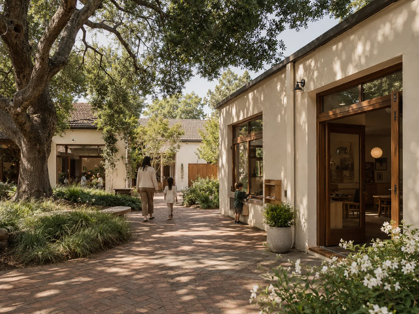The Bilton School — Oak-shaded courtyard between cream stucco buildings with open classroom doors